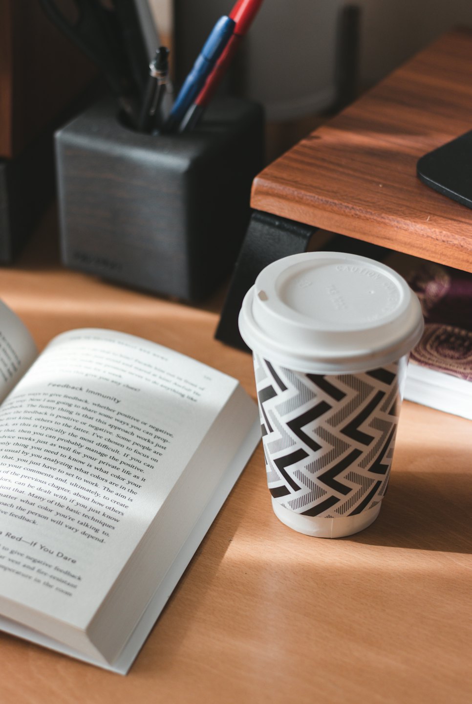 Wooden desk with an open book and coffee cup.